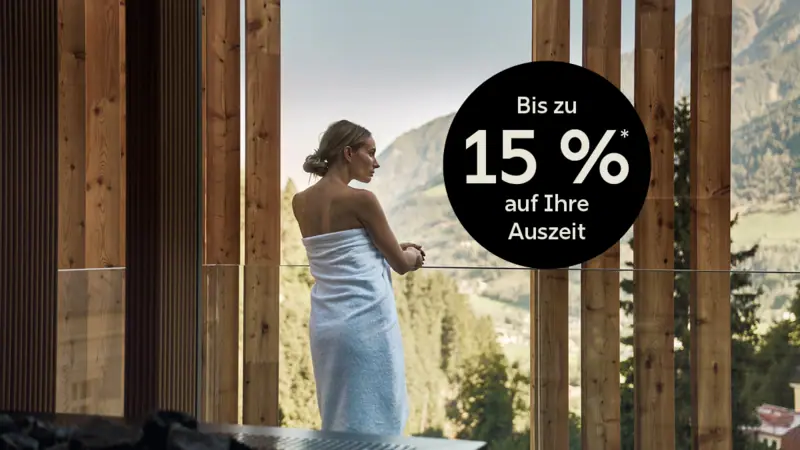 Eine Frau in ein Handtuch gehüllt blickt aus dem Fenster.