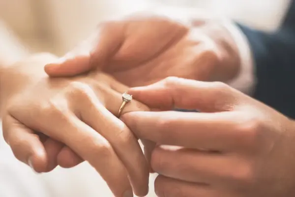 Ein Mann steckt seiner Frau den Ehering an den Ringfinger. 