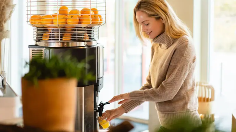 Frühstück im A--ROSA Sylt Eine Frau gießt Orangensaft aus einem Saftspender.