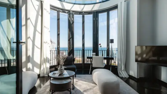 Wohnzimmer mit großem Fenster mit Blick auf das Meer, ausgestattet mit einer Couch, einem Couchtisch und einer Vase und einen Fernseher..