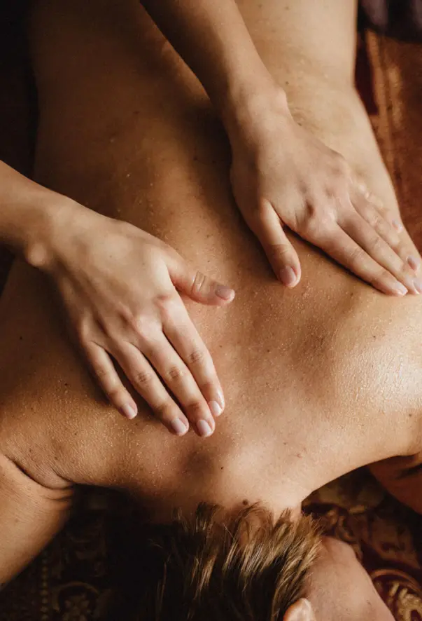 Zwei Hände sind für eine Massage auf dem Rücken einer Person platziert. 