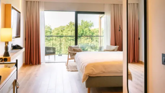 Elegant hotel bedroom featuring a large bed with plush pillows and a prominent mirror.