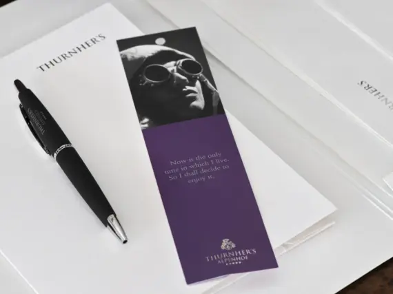 A purple bookmark and a black ballpoint pen lie on a white pad.