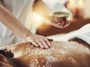 Massage mit Salzpeeling auf dem Rücken einer Frau.
