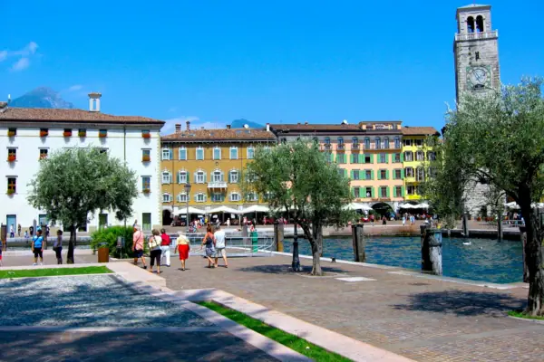 Eine Gruppe von Menschen spaziert auf einem Weg nahe am Wasser.