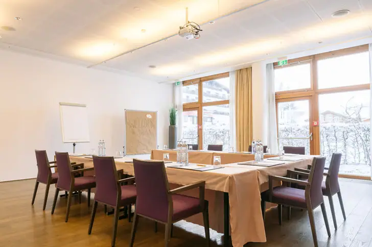 Ein Meetingraum mit einem Tisch und Stühlen.