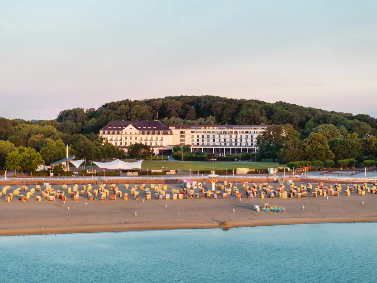 Strand mit Stühlen und Bäumen im Hintergrund.