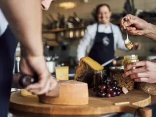 Hands holding a spoon over food.