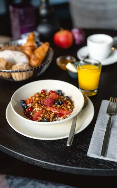 A bowl of fruit and muesli on a table.