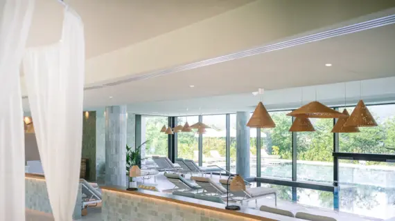 Indoor pool area with chairs and a large window overlooking the pool.