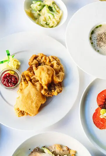 A table set with a variety of dishes including salads, vegetables, and garnished plates.