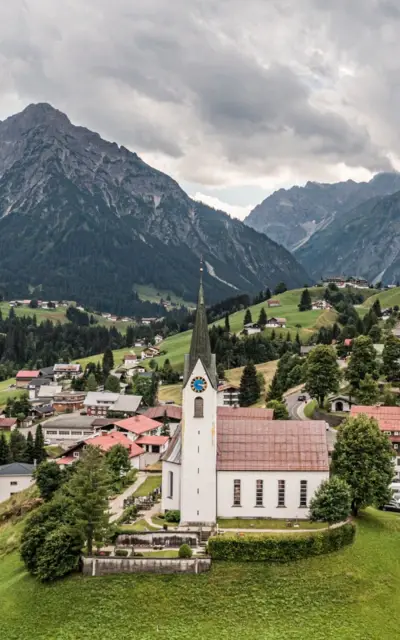 Kirche in einem Tal mit Bergen im Hintergrund.