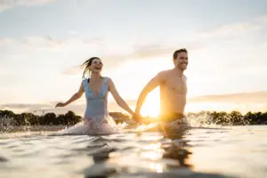 Baden Ein Mann und eine Frau halten sich im Wasser an den Händen.