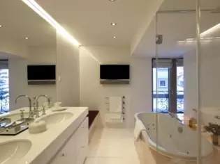 A large bathroom with a free-standing bathtub, two washbasins and a TV.