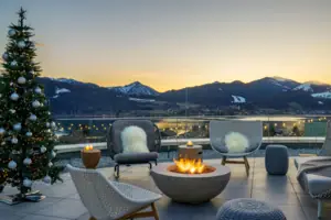 Tegernsee Weihnachten Feuerstelle mit Stühlen und Blick auf schneebedeckte Berge im Hintergrund