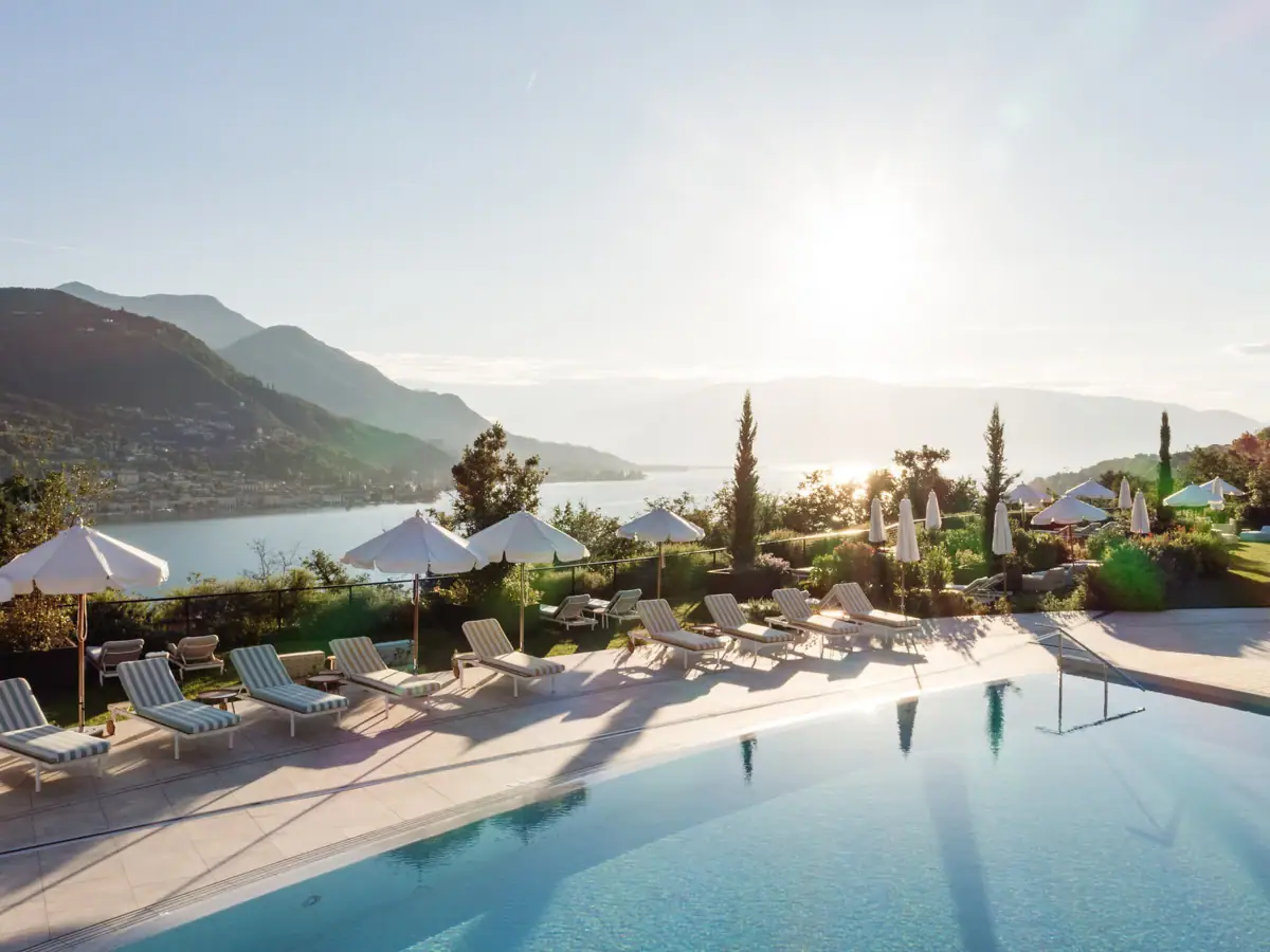Ein Pool mit Liegestühlen und Sonnenschirmen am Wasser.