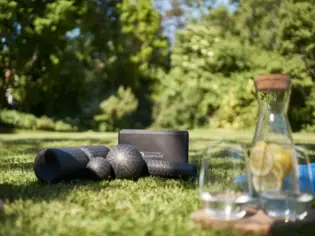 Yogamatten und ein Glas Wasser auf Gras.
