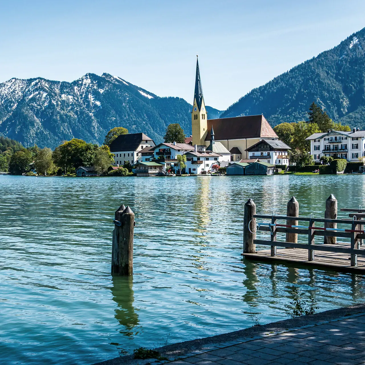 Ein See mit einer Kirche und Bergen im Hintergrund.