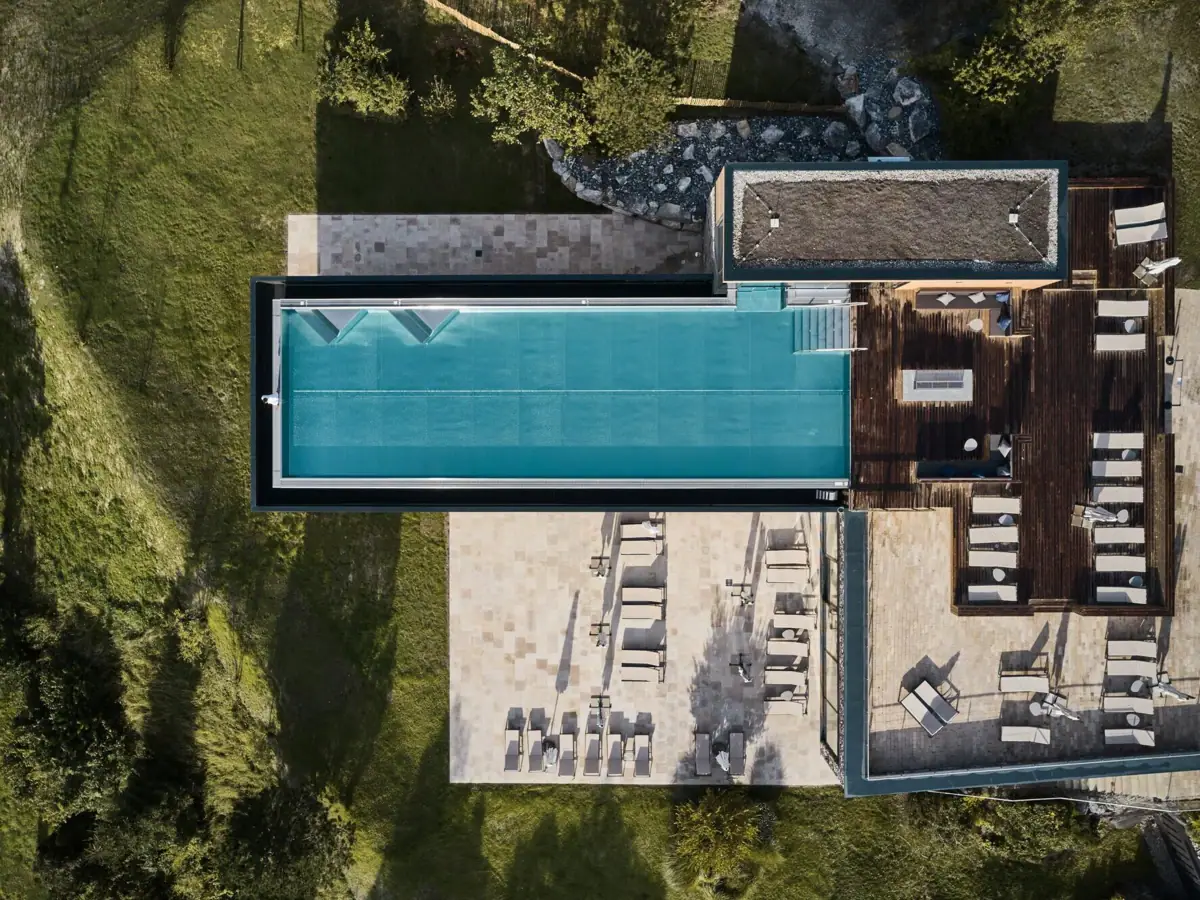 Outdoor Infinity Pool im Ifen Hotel Kleinwalsertal aus der Vogelperspektive Außenpool auf einem Gebäude mit Bäumen drum herum..