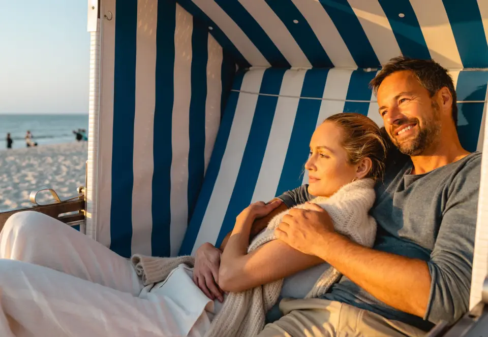 Ein Mann und eine Frau laufen an einem Strand.