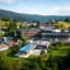 Das Ifen Hotel im Kleinwalsertal mit einem Swimmingpool in der Mitte eines Bergdorfes, umgeben von Bäumen und Gras.