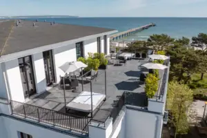 Ein Gebäude mit einer Terrasse und Sonnenschirmen mit Blick auf das Wasser.