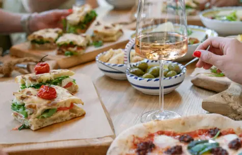 Person sits at a table with various dishes, including focaccia and olives.