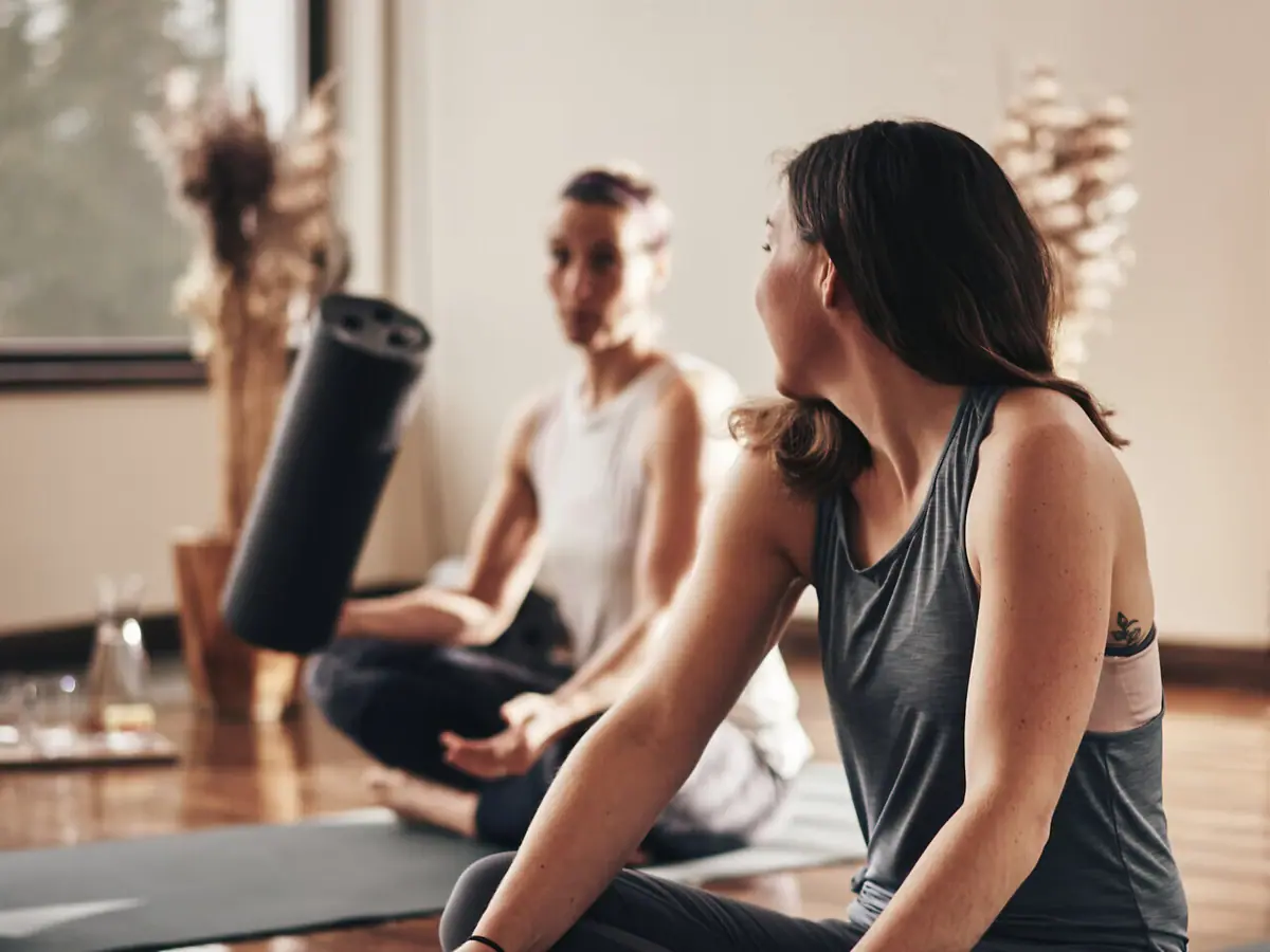 Eine Gruppe von Frauen sitzt auf Yogamatten.