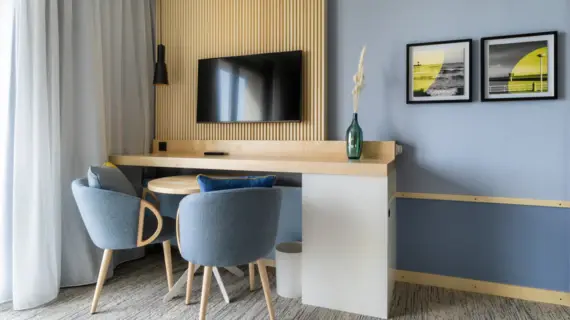 Ein Schreibtisch mit zwei grauen Sesseln über dem ein Fernseher hängt.