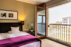 Schlafzimmer mit offenem Balkonzugang und elegantem Bett.