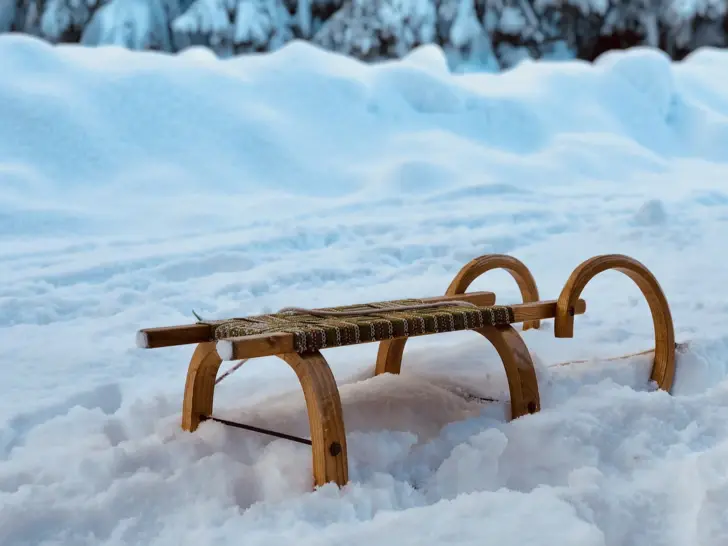 Ein Schlitten steht auf einem schneebedecktem Weg.