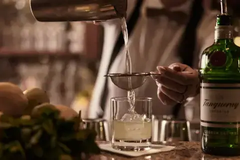 Eine Person gießt ein Getränk in ein Glas ein.