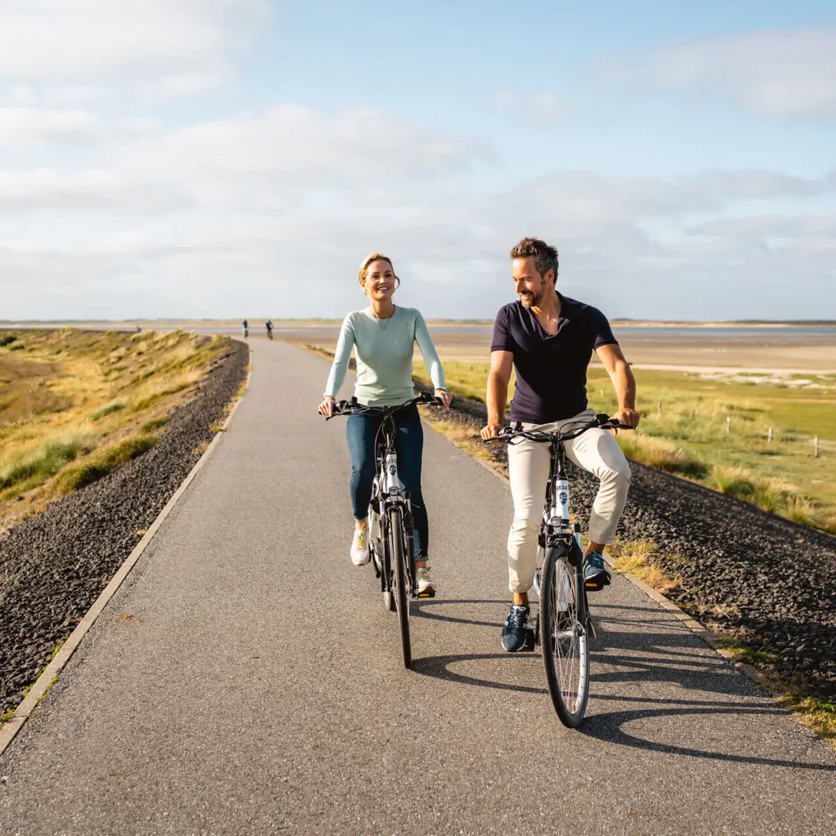 Ein Mann und eine Frau fahren auf einer Straße Fahrrad.
