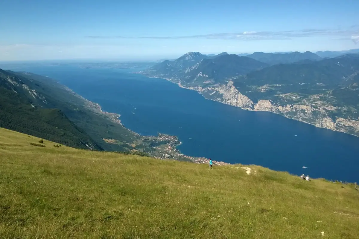 Eine Person steht auf einem Berg und blickt auf einen See.