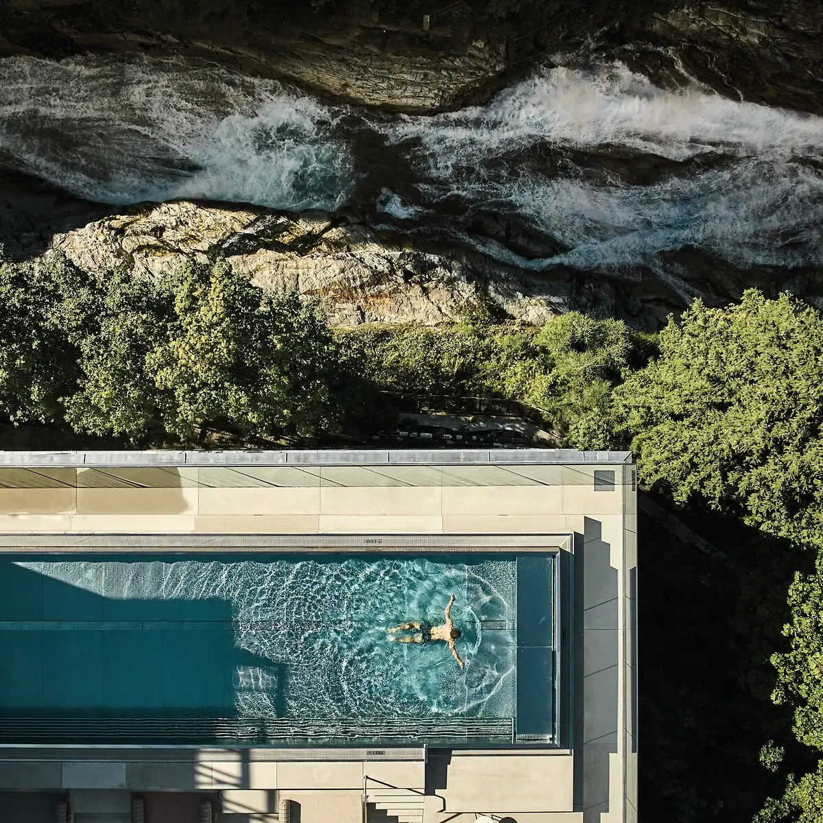 Person schwimmt im Pool vom A-ROSA Straubinger Grand Hotel Bad Gastein neben dem Gasteiner Wasserfall..