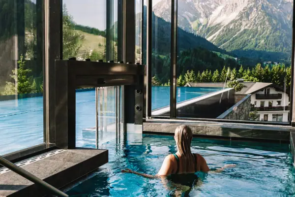 Pool Eine Frau im Pool mit Bergen im Hintergrund.