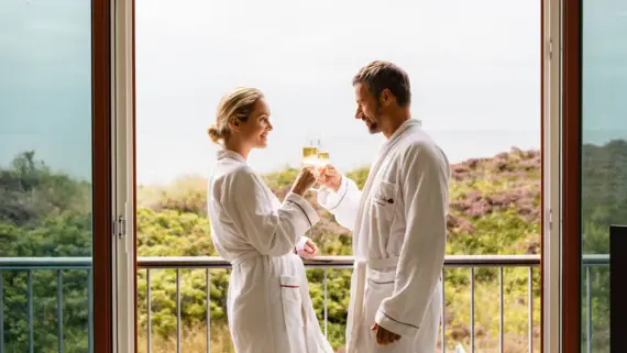 Ein Mann und eine Frau in Bademantel halten Champagnergläser.
