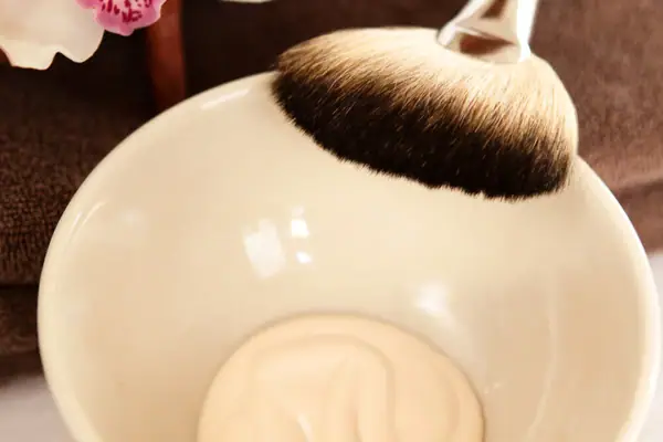 Ein Pinsel über einer Schale mit weißer Flüssigkeit.