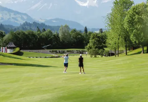 Zwei Personen stehen auf einer großen Wiese und spielen Golf.