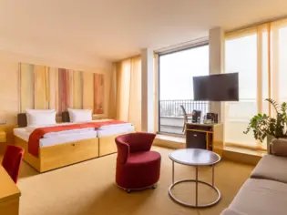 Ein Hotelzimmer mit einem großen Bett, einem roten Sessel und einem Sofa.