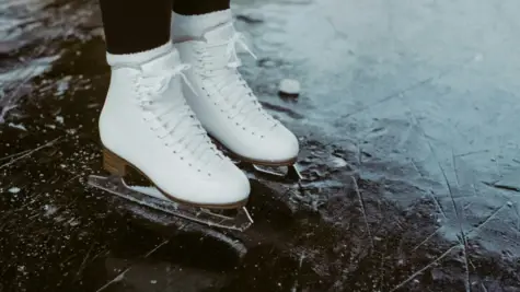 Zwei Füße mit Schlittschuhen stehen auf einer Eisfläche.