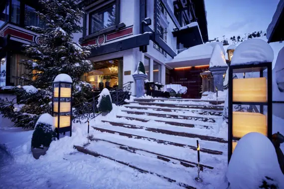 A snow-covered staircase leads to a hotel entrance.