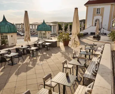 Eine Terrasse mit Tischen und Sonnenschirmen.