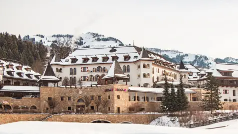 Winterliche Landschaft mit einem Gebäude im Stil eines Schlosses und schneebedeckten Bäumen.