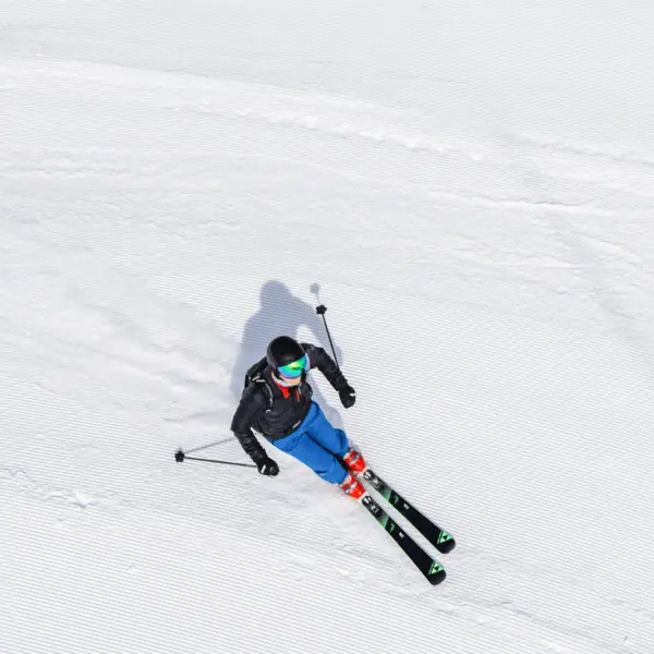 Person fährt auf Skiern eine verschneite Piste hinunter.