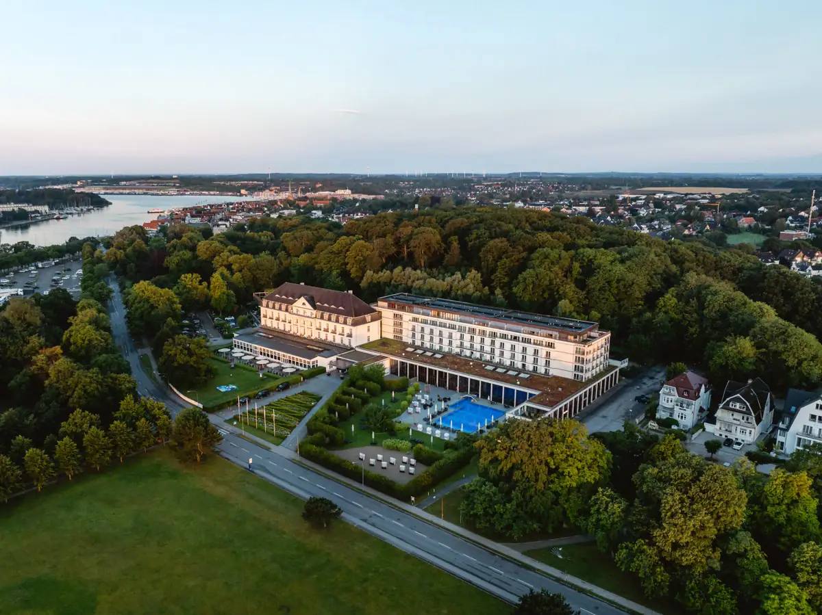 Das AROSA Travemünde von oben fotografiert mit Außenpool, umgeben von Bäumen.