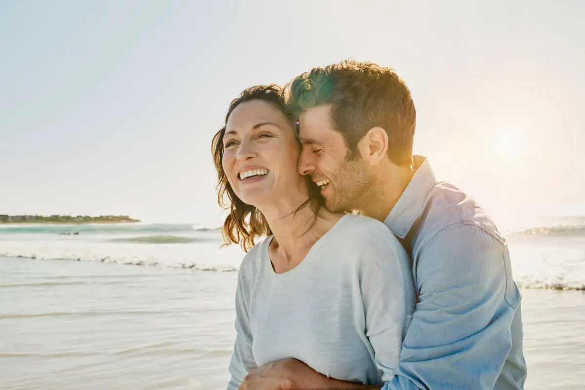 Ein Mann und eine Frau umarmen sich am Strand.