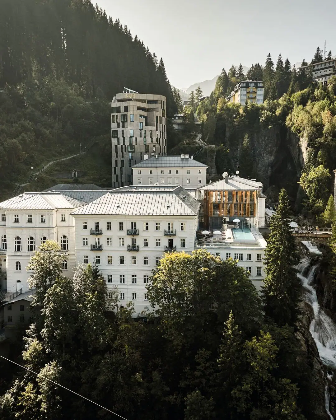 Eine Gruppe von Gebäuden mit Bäumen und Bergen im Hintergrund.