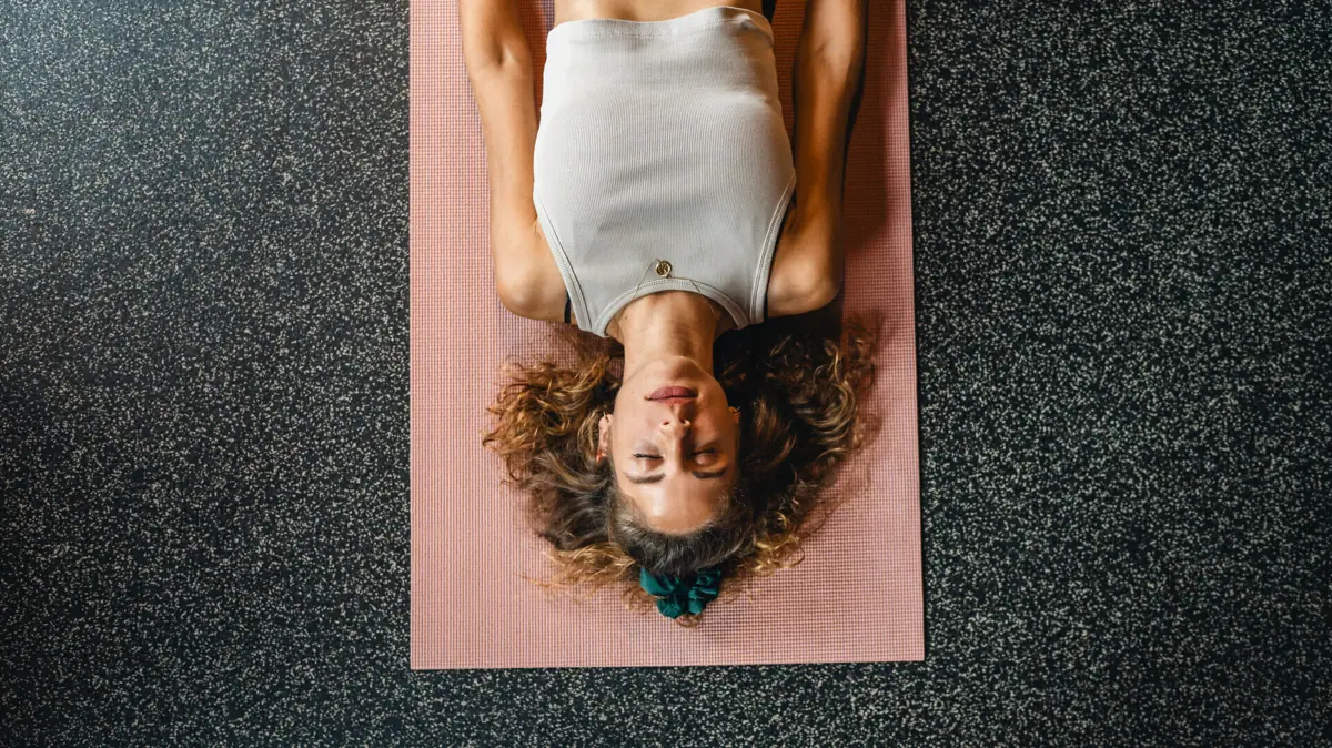 Eine Frau liegt auf einer Yogamatte.