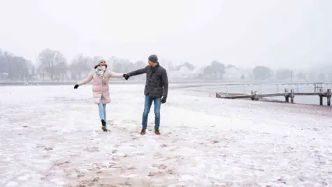 Ein Mann und eine Frau halten Hände im Schnee.